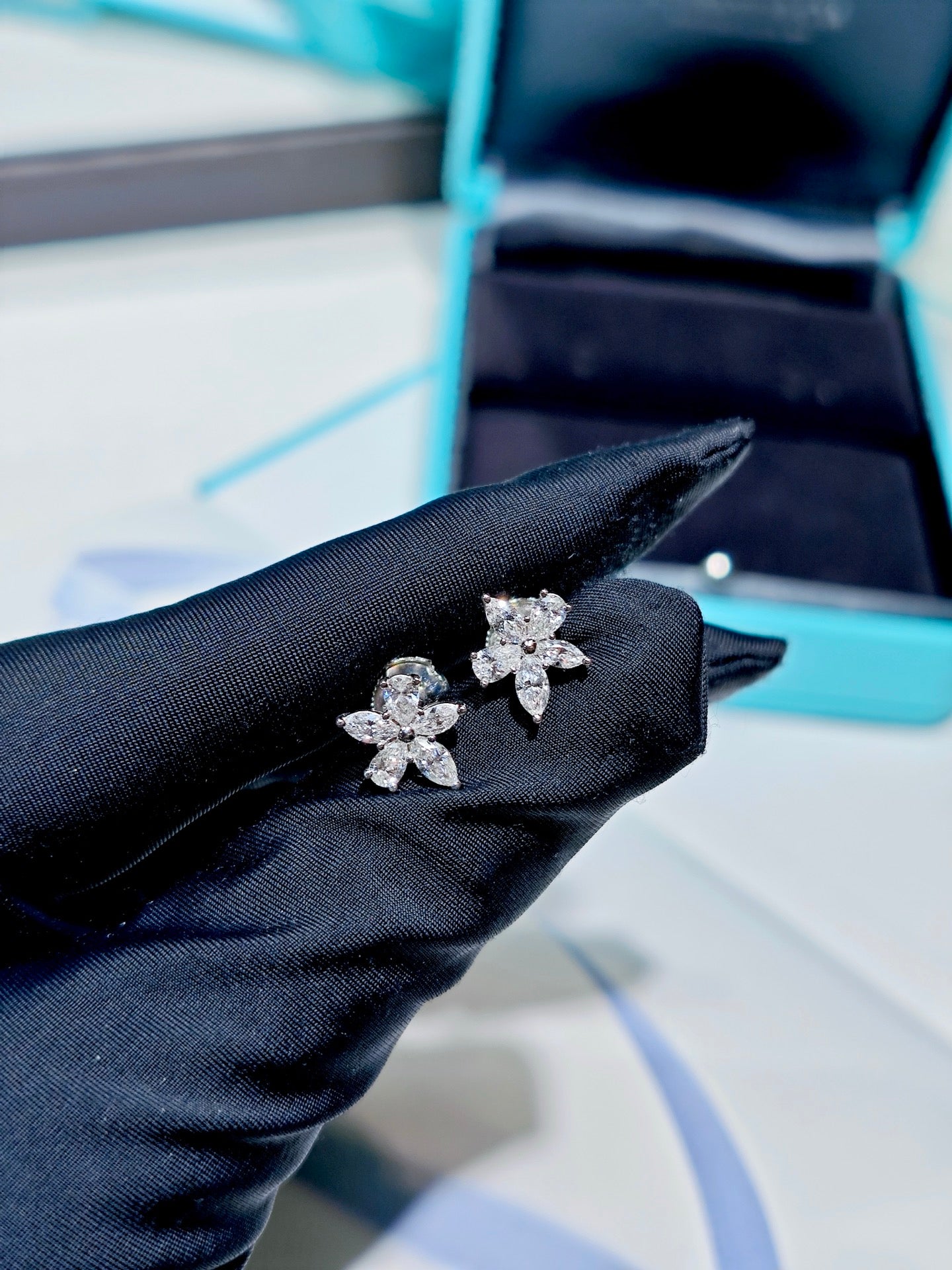 Tiffany Victoria Mixed Cluster diamond earrings held in a black glove
